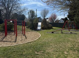 Außengelände mit Blick auf Klettergerüst, Rutsche, Schaukel und Wippe